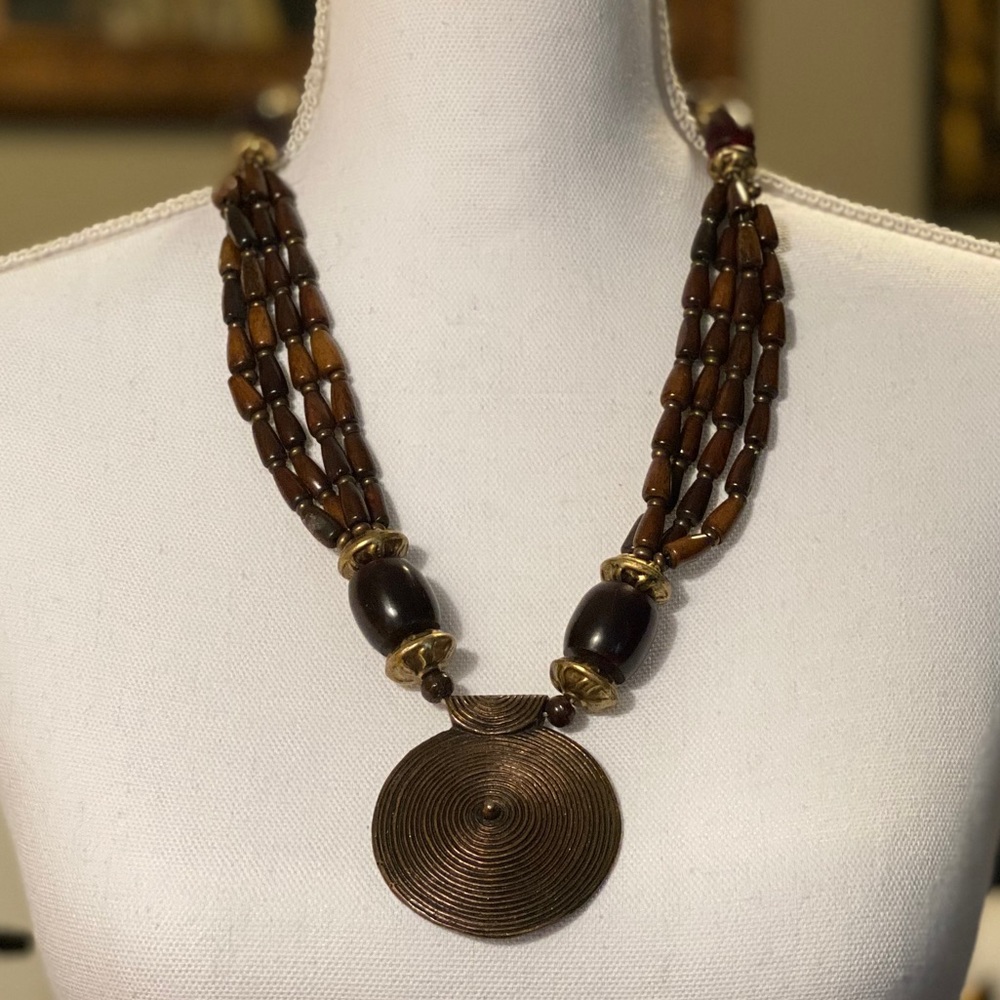 Brown beaded necklace with solid metal medallion.